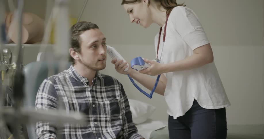 A nurse takes a man's temperature with an ear thermometer