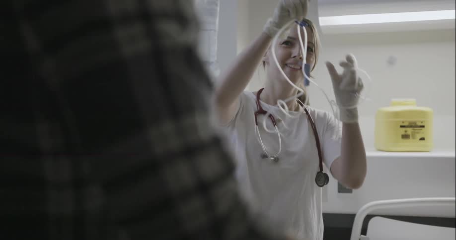 A nurse prepares an iv while speaking with a man