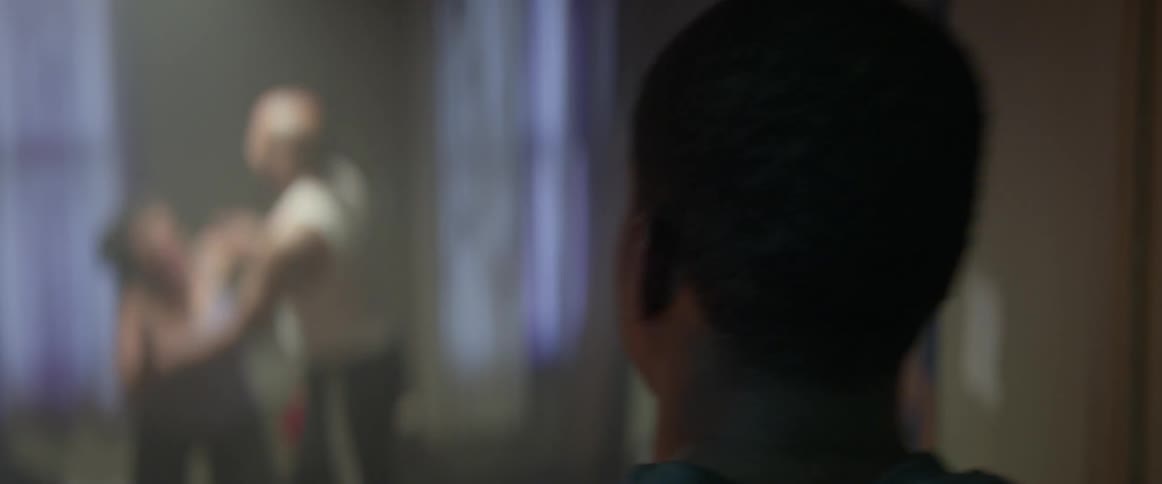 A young boy is walking into a bedroom while his parents are fighting