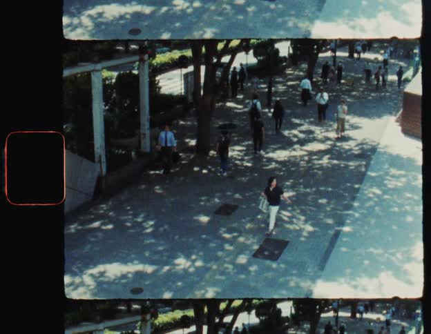 A small crowd of people walk up and down the sidewalk of a small city