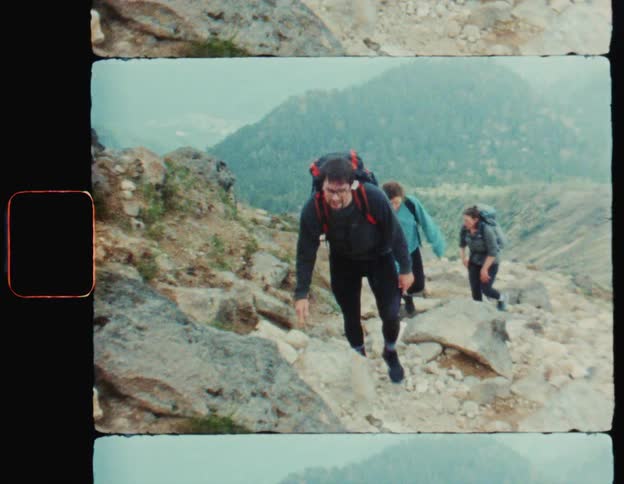 Group of three people climbing rocks through the mountains