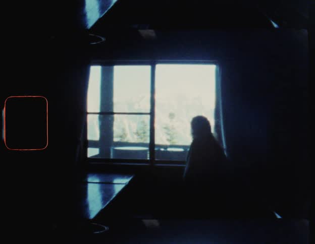 Silhouette of a woman sitting by a window with a view of a large mountain range