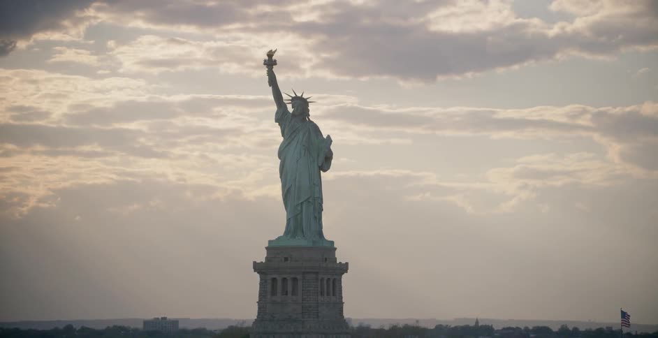 The statue of liberty sits under a cloudy sky