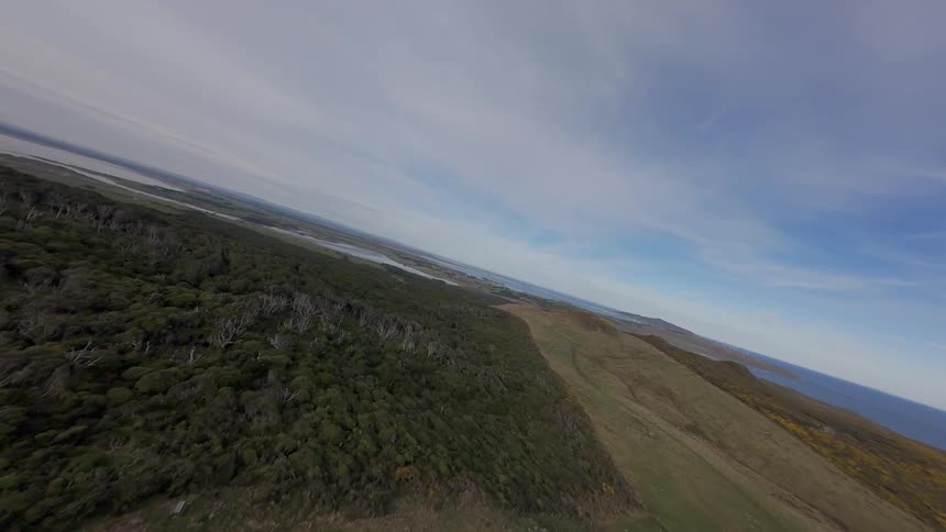 FPV aerial panorama of rocky hill with the sea in the background