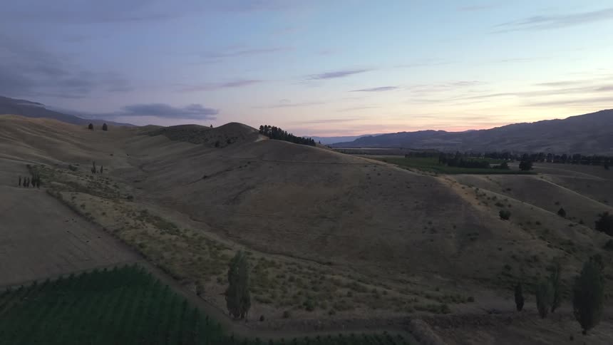 Aerial view of a crop field leading into grass covered hills