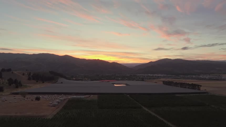 Aerial scene of an agricultural area and a reservoir with the silhouette of mountains in the background and a purple sky