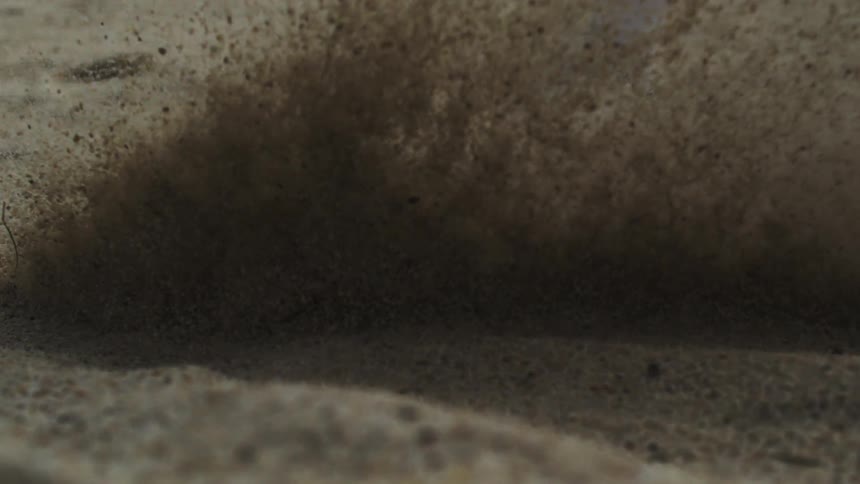 Golf club hitting a white ball in the sand