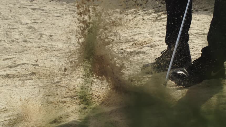 A man hits the golf ball out of the sand trap
