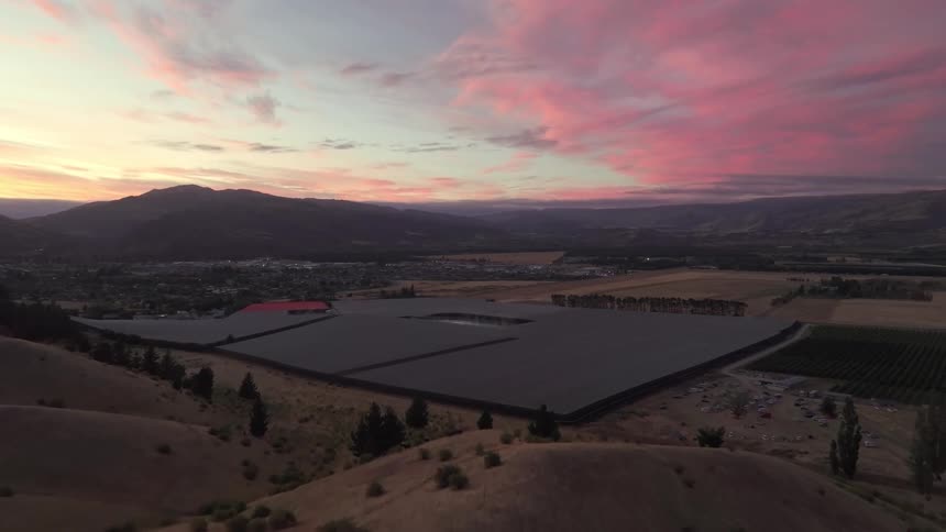 Aerial panorama of an agricultural field surrounded by mountains against a purplehued sky