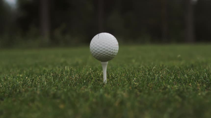 White golf ball on a stand on the grass