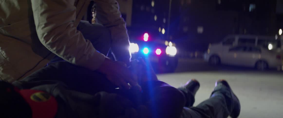 A person is lying on the ground being handcuffed