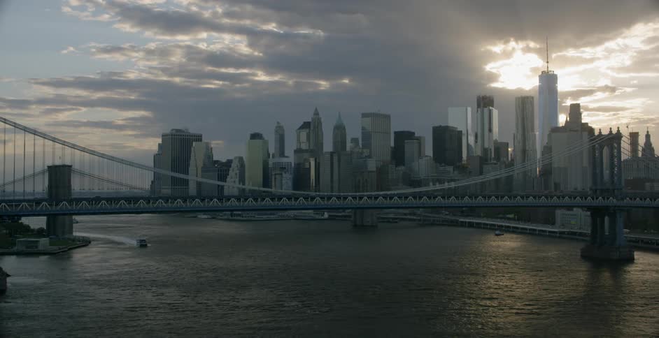 A city bridge crosses a river with skyscrapers in the background