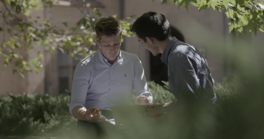 Two men look through a newspaper and talk