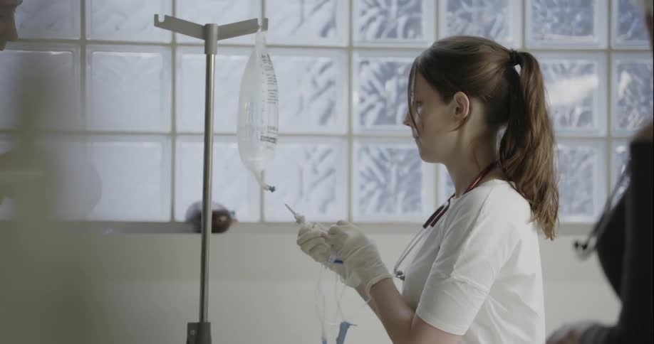 A woman attaches a tube to an iv bag