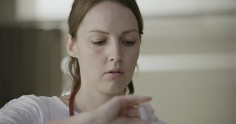 A nurse prepares a syringe to inject a patient