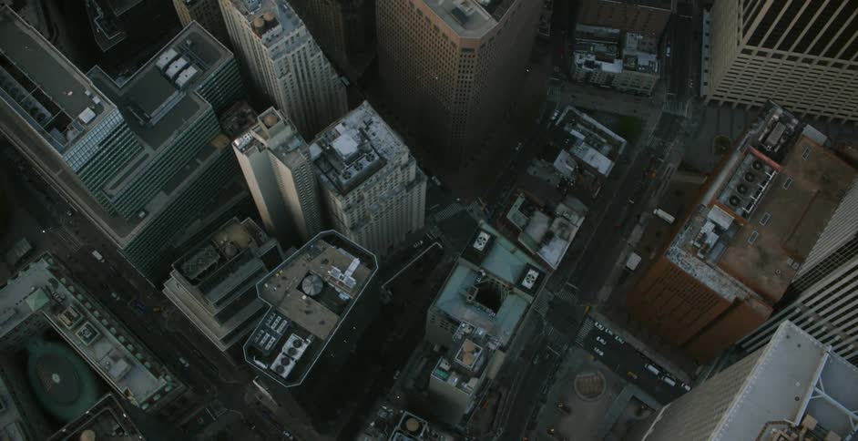 Cars travel below on the roads between these tall buildings