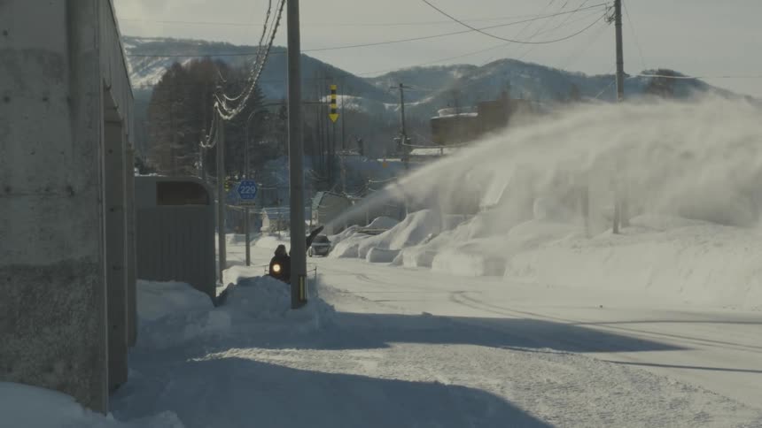 A person is riding a snow blower down the road