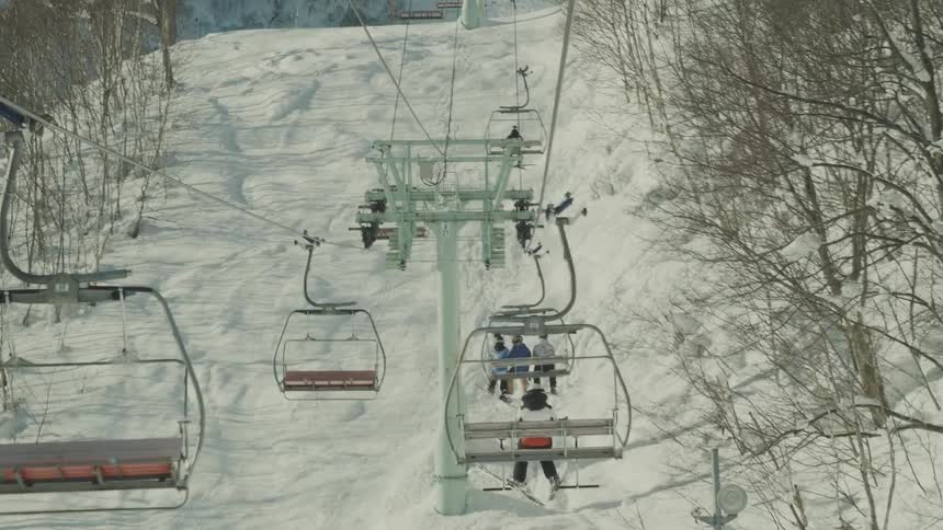 People in cable cars moving through snowcovered mountains