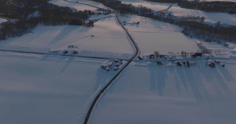 Aerial view of a snowcovered landscape with a road cutting through it
