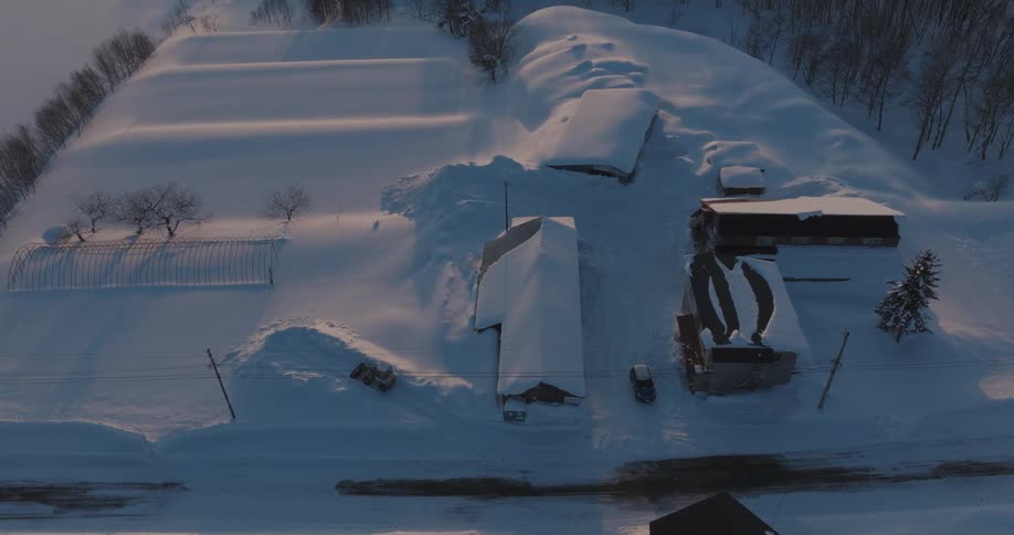 Top view of a tractor removing snow from a path and surrounding houses