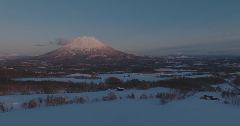 Aerial of a rural housing community at the base of a tall mountain during the wintertime