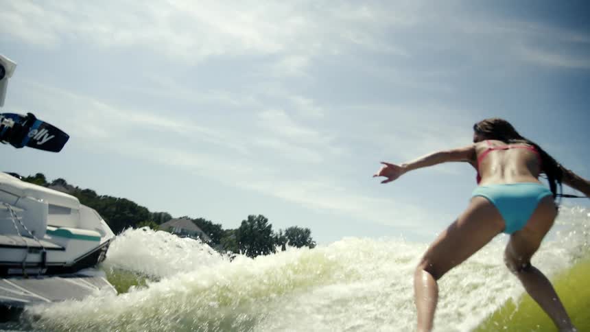 Woman surfing a wave and a speedboat next to it