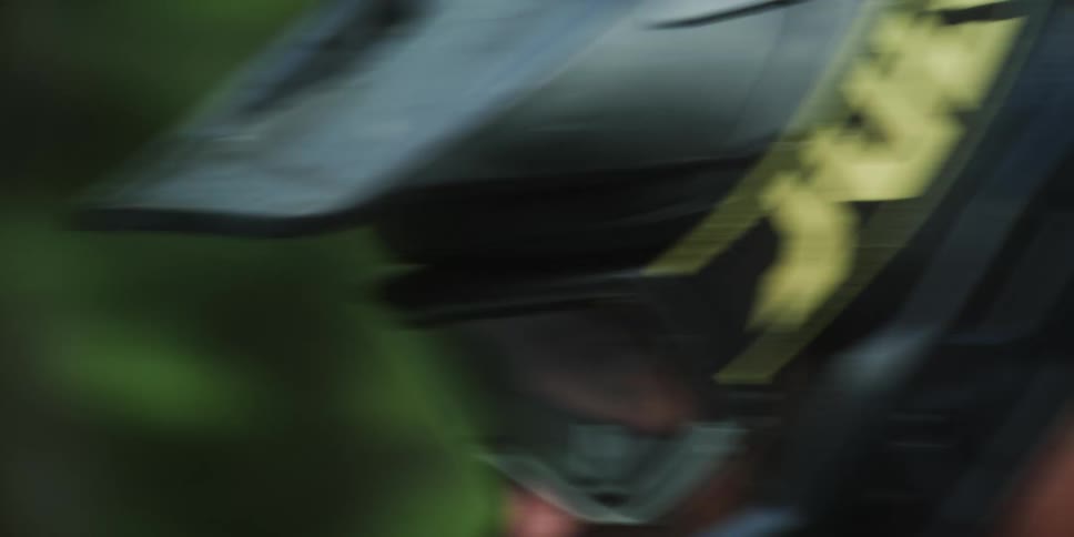 The face of a person wearing a cycling helmet with goggles and riding a mountain bike fast downhill