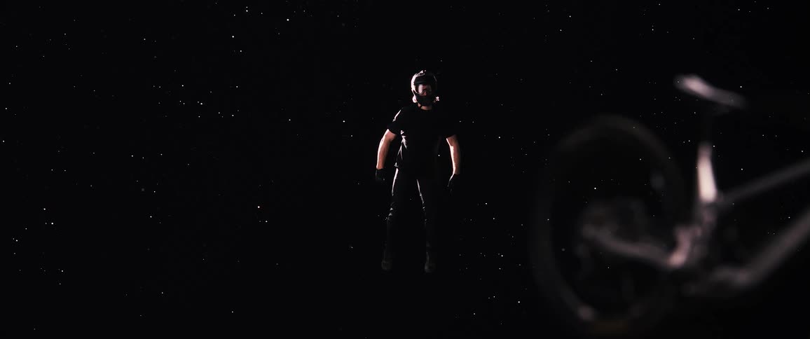 Man in mountain bike garment floats in space with part of a bicycle floating in front of him