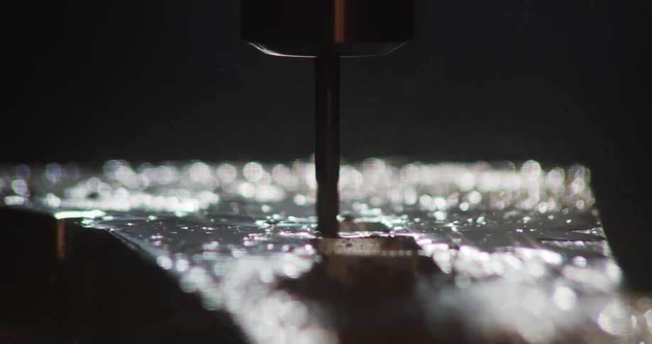 A closeup view of a drill bit in contact with a surface creating metallic shavings