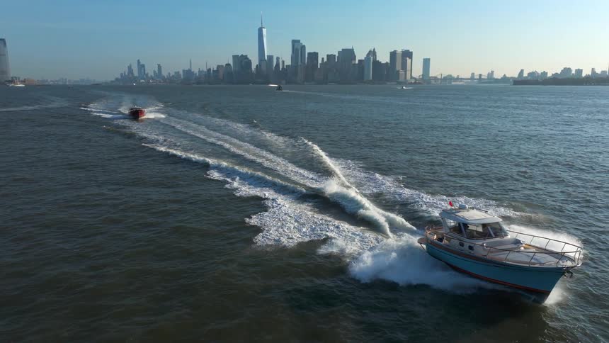 Aerial view of boats traveling at sea with a metropolis in the background