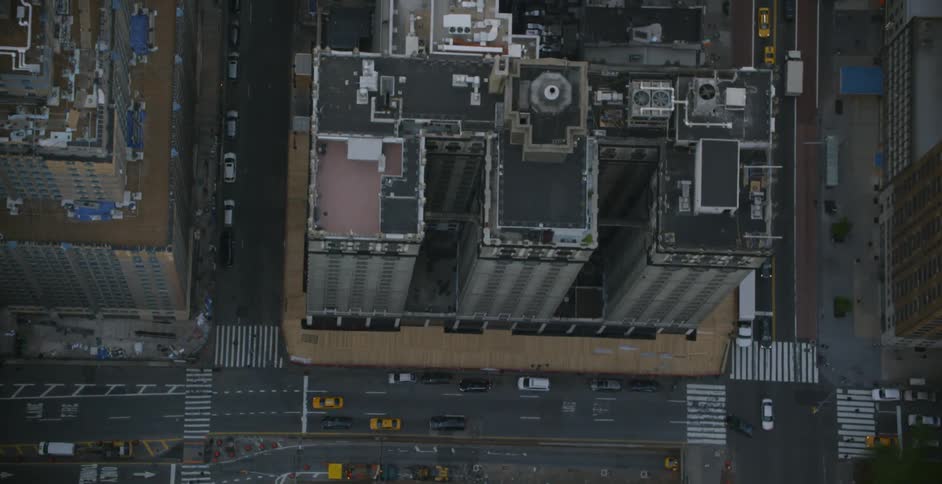 Vehicles drive on a city street surrounded by tall buildings