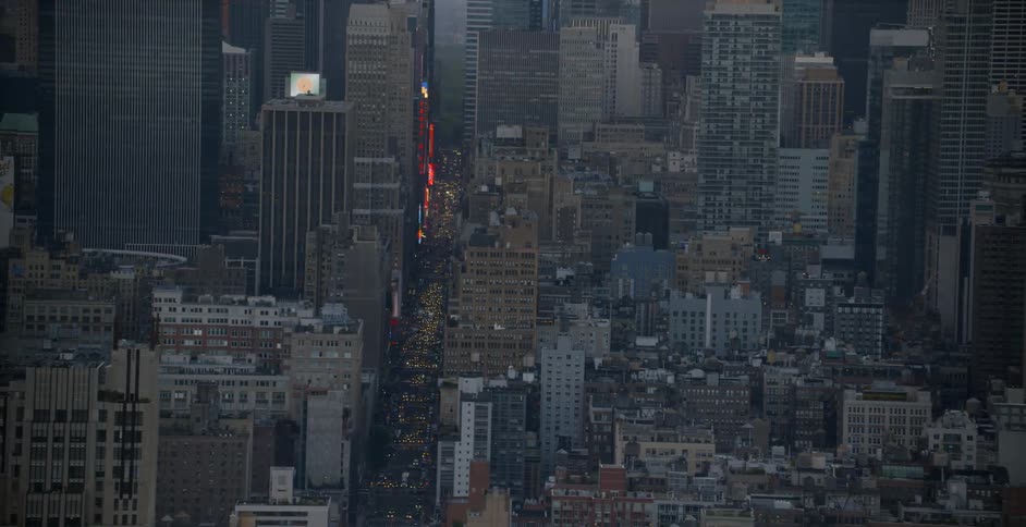 The city below has bright lights in the distance
