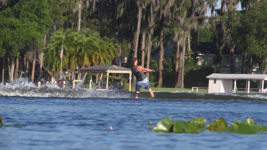 A person holds a cord and rides along the water