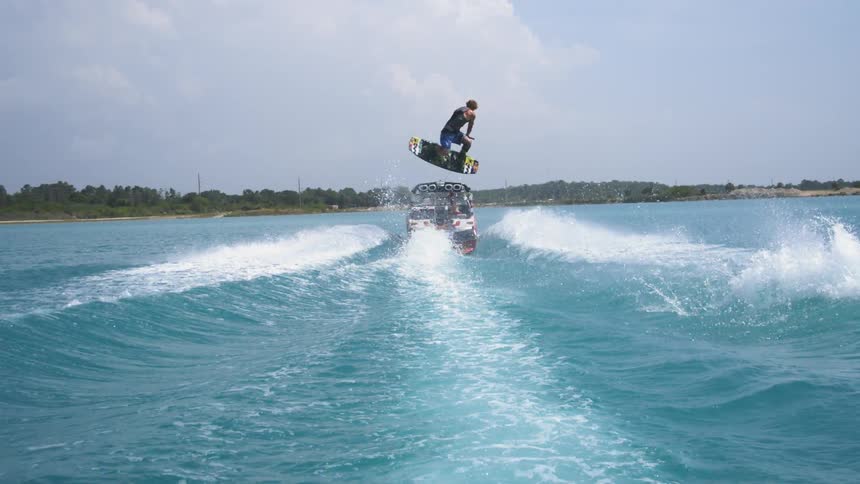 Boat pulling a water skier as he jumps the waves made by the boat