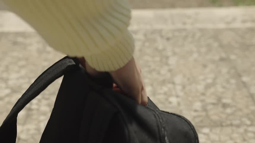 Hands of a person opening their backpack from behind