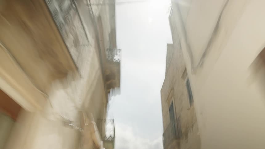 A narrow alleyway between two tall white buildings with balconies