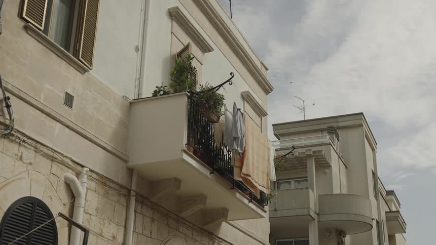 The top half of two houses are shown with a plant and clothes on ones balcony