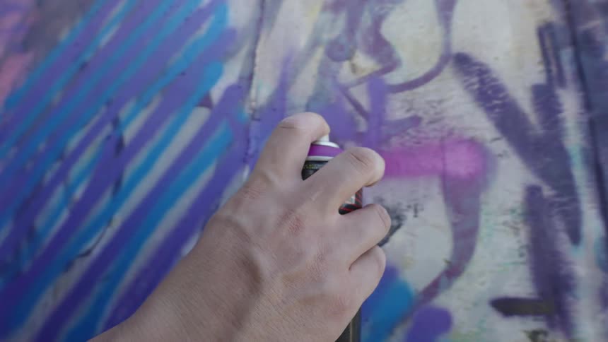 A person is spray painting the wall outside