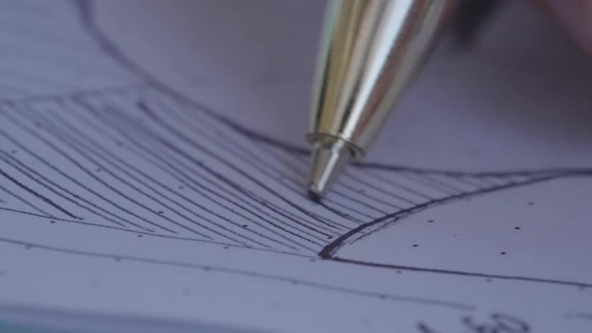 A closeup of a pen drawing on paper creating a curved line on a technical drawing or blueprint