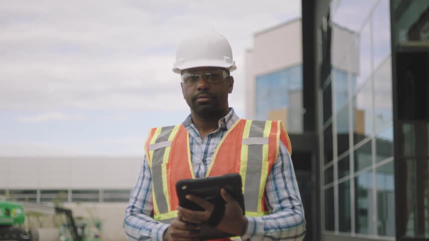 Worker holding a tablet and wearing a protective helmet