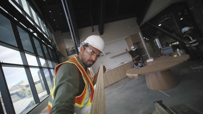 Man with helmet and high visibility vest holding a wooden slat