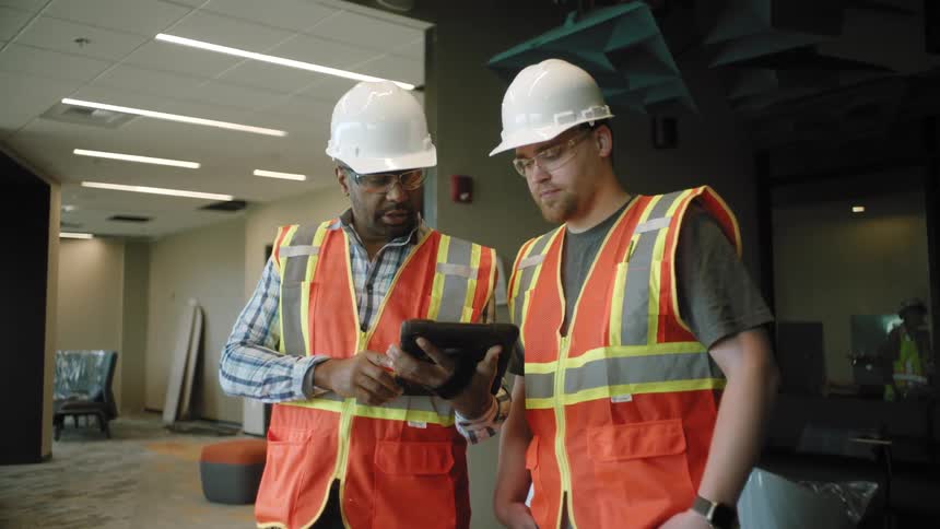 Two construction managers discuss the content of a tablet theyre both looking at