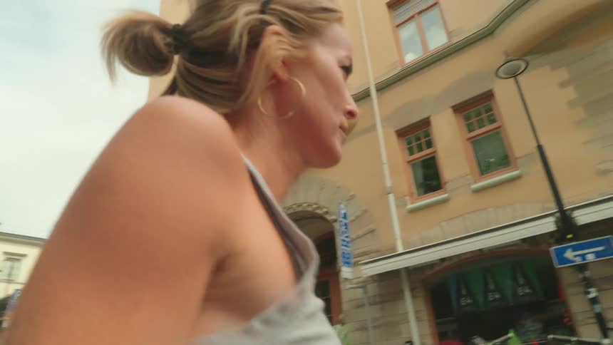 Blonde woman with hoop earrings and a gray top walks down the street in the neighborhood