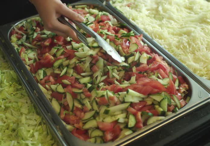 Hand with a spatula serving salad in a restaurant