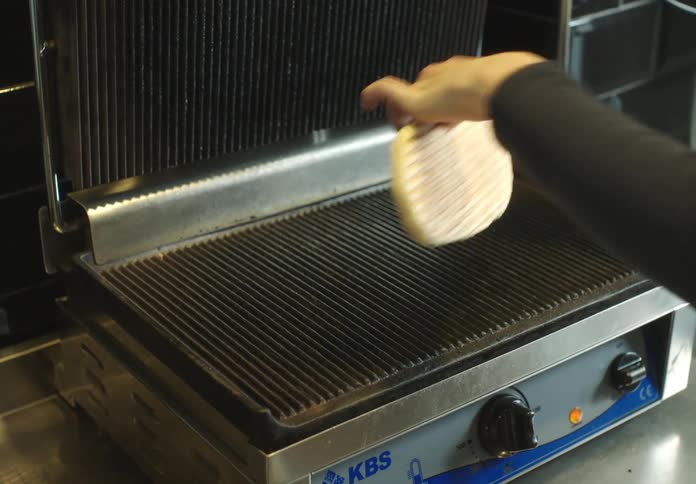 Hand placing a bread in an electric press