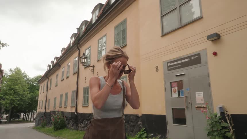 Woman walks down the road while putting sunglasses on her head