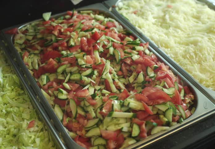 Hand with a spatula picking up salad