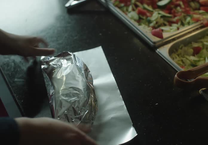 Hands wrapping a snack in aluminum foil