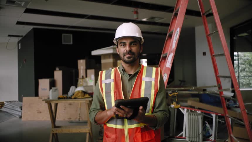 Man at a construction site indoors holding a tablet