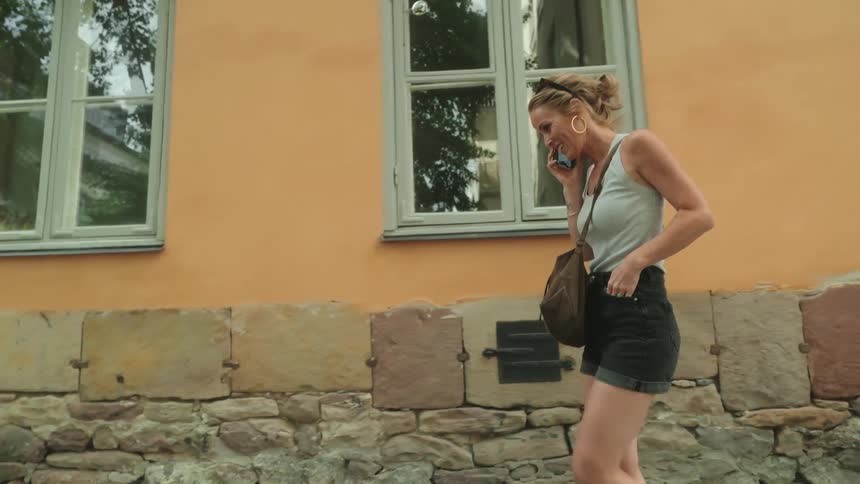 A woman is walking as she talks on her cell phone